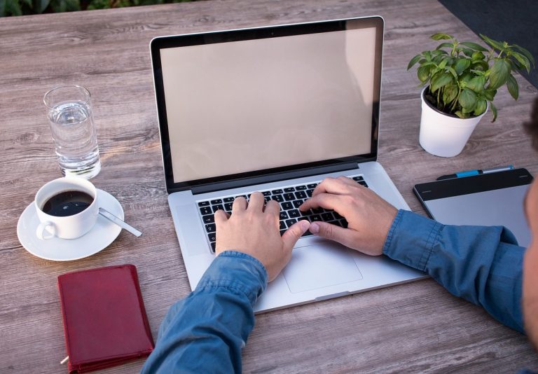 man working on his computer next to a potted plant